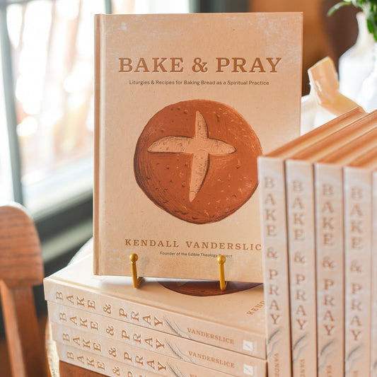 Book titled 'Bake & Pray' by Kendall Vanderslice on a wooden table with a blurred background