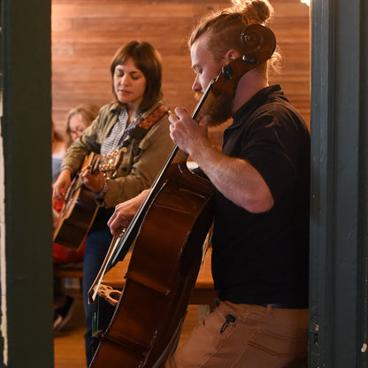Two musicians playing instruments in a room with wooden walls.
