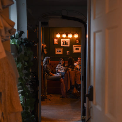 People sitting at a table in a warmly lit room with framed pictures on the wall.