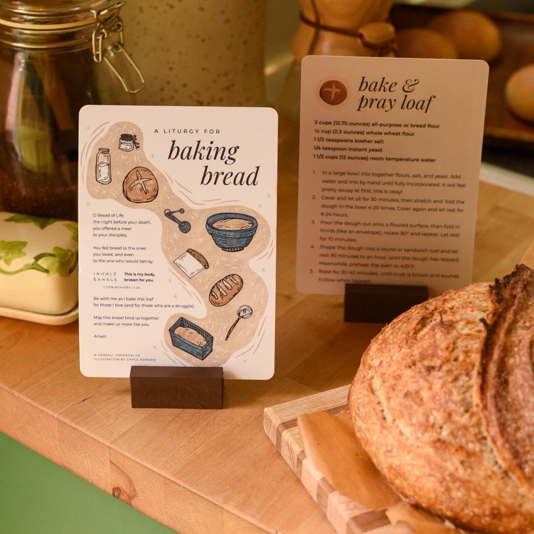 Bread on a wooden cutting board with baking instructions and tools in the background.