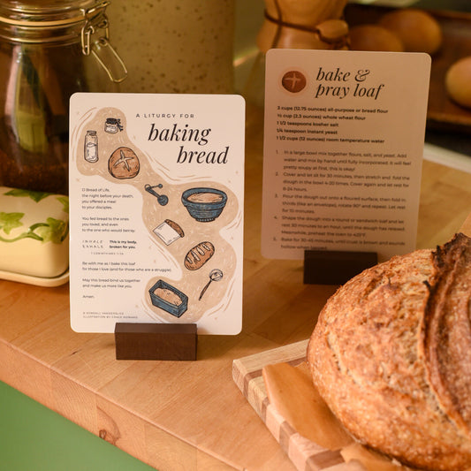 Bread on a wooden cutting board with baking instructions and tools in the background.